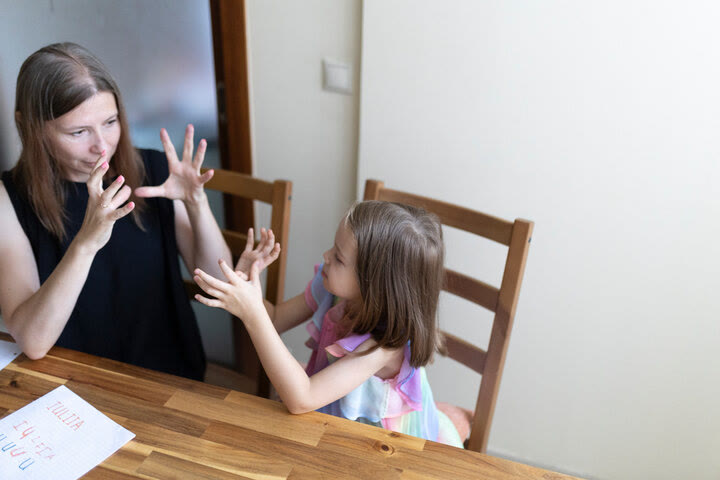 Maestra y niña comunicándose en lenguaje de señas
